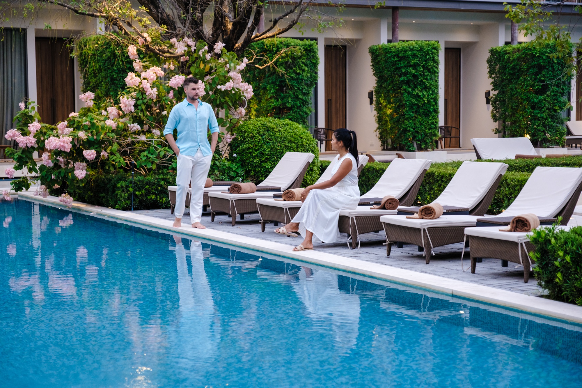 Luxury 5 star hotel pool in Asia. A couple of men and women on vacation at a luxury hotel resort, men and women by the pool in the evening